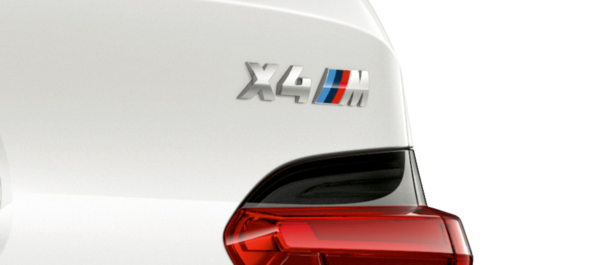BMW X4 M, oznaka modela. BMW X4 M v barvi Alpine White, zunanjost, povečan posnetek zadnjega dela z oznako modela.