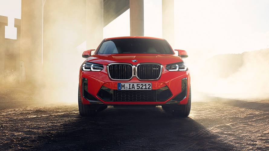 BMW X4 M, F98, LCI, osvežitev 2021, kovinska barva Toronto Red, pogled od spredaj pred stebri pod mostom