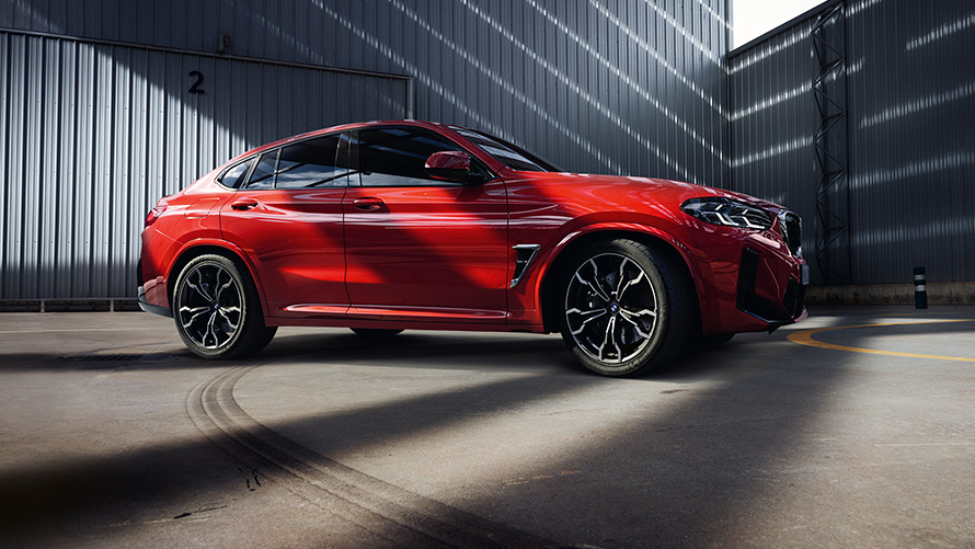 BMW X4 M, F98, LCI, osvežitev 2021, kovinska barva Toronto Red, stranski pogled pred tovarniško stavbo