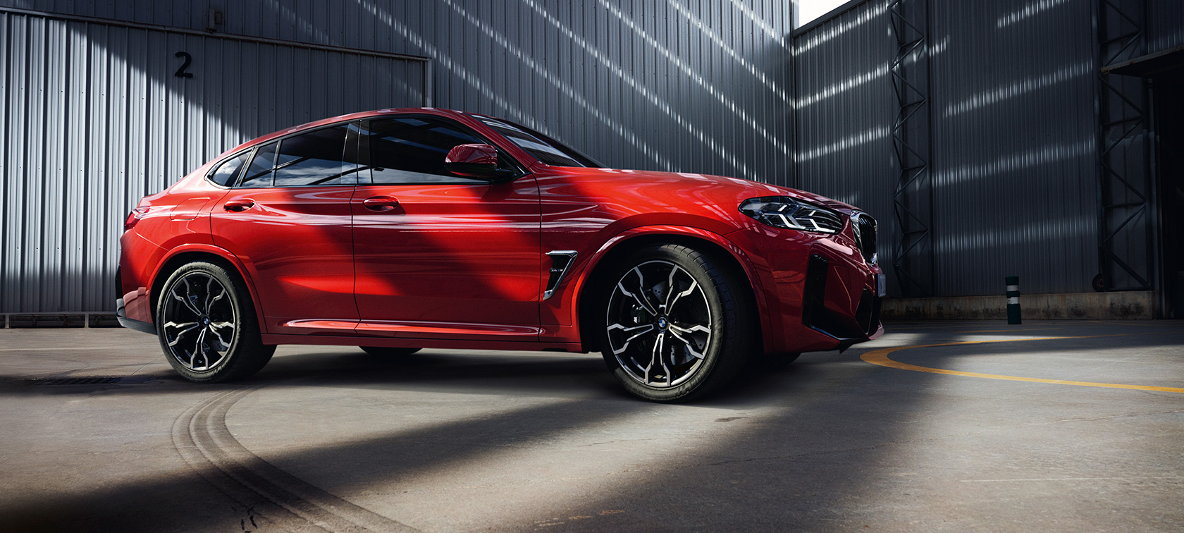 BMW X4 M, F98, LCI, osvežitev 2021, tričetrtinski pogled od spredaj BMW X4 M, F98, LCI, osvežitev 2021, kovinska barva Toronto Red, tričetrtinski pogled od spredaj v tovarniški stavbi