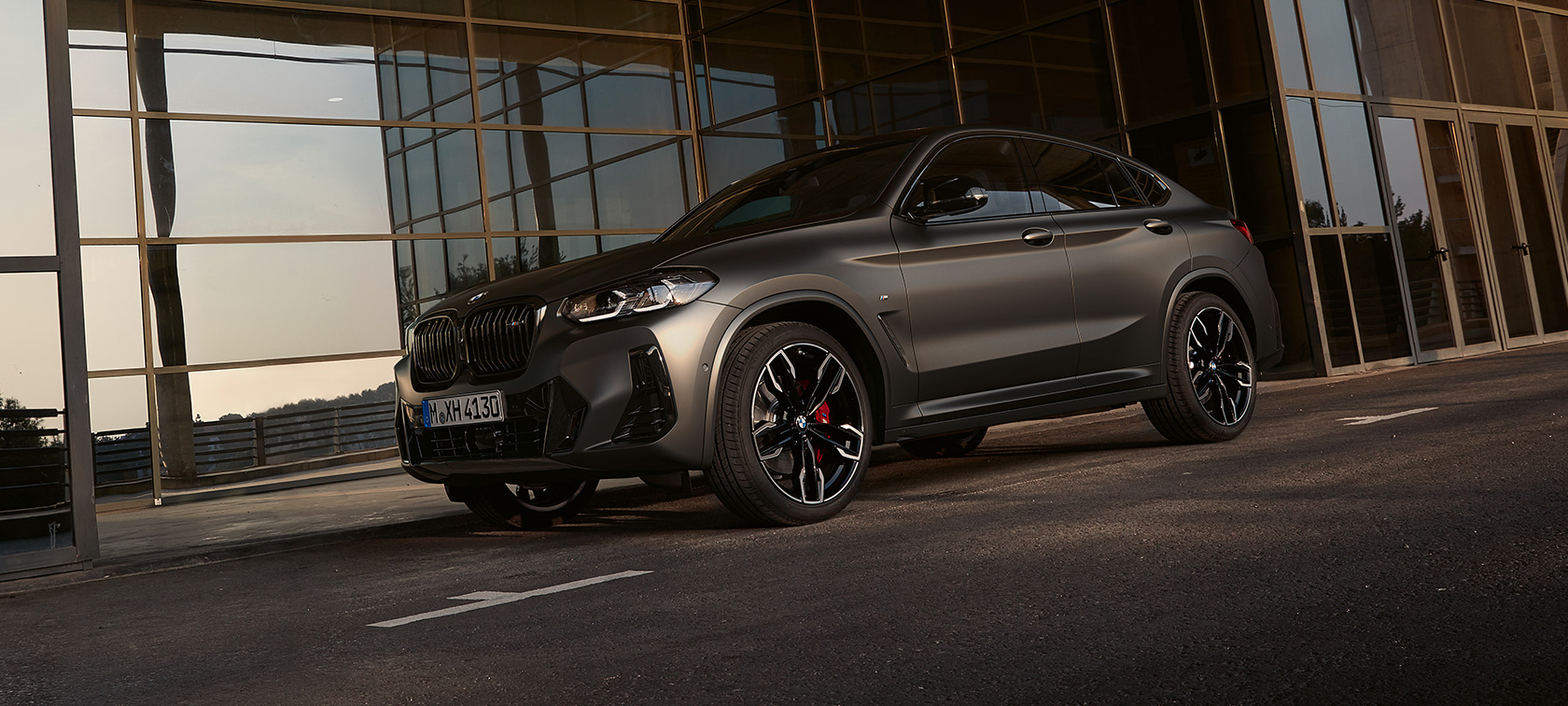 BMW X4 M40i, G02, LCI, osvežitev 2021, tričetrtinski pogled od spredaj BMW X4 M40i, G02, LCI, osvežitev 2021, tričetrtinski pogled od spredaj pred stekleno fasado