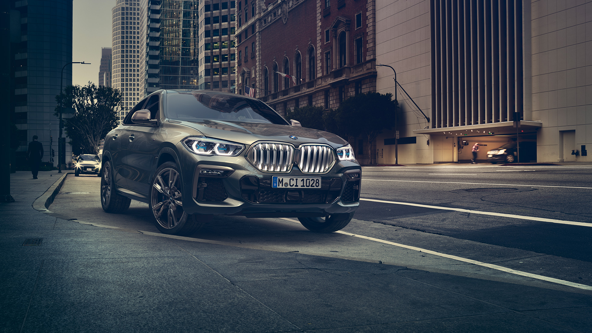 BMW X6 M50i med mirovanjem BMW X6 M50i, tričetrtinski pogled od spredaj med mirovanjem pred mestnim okoljem
