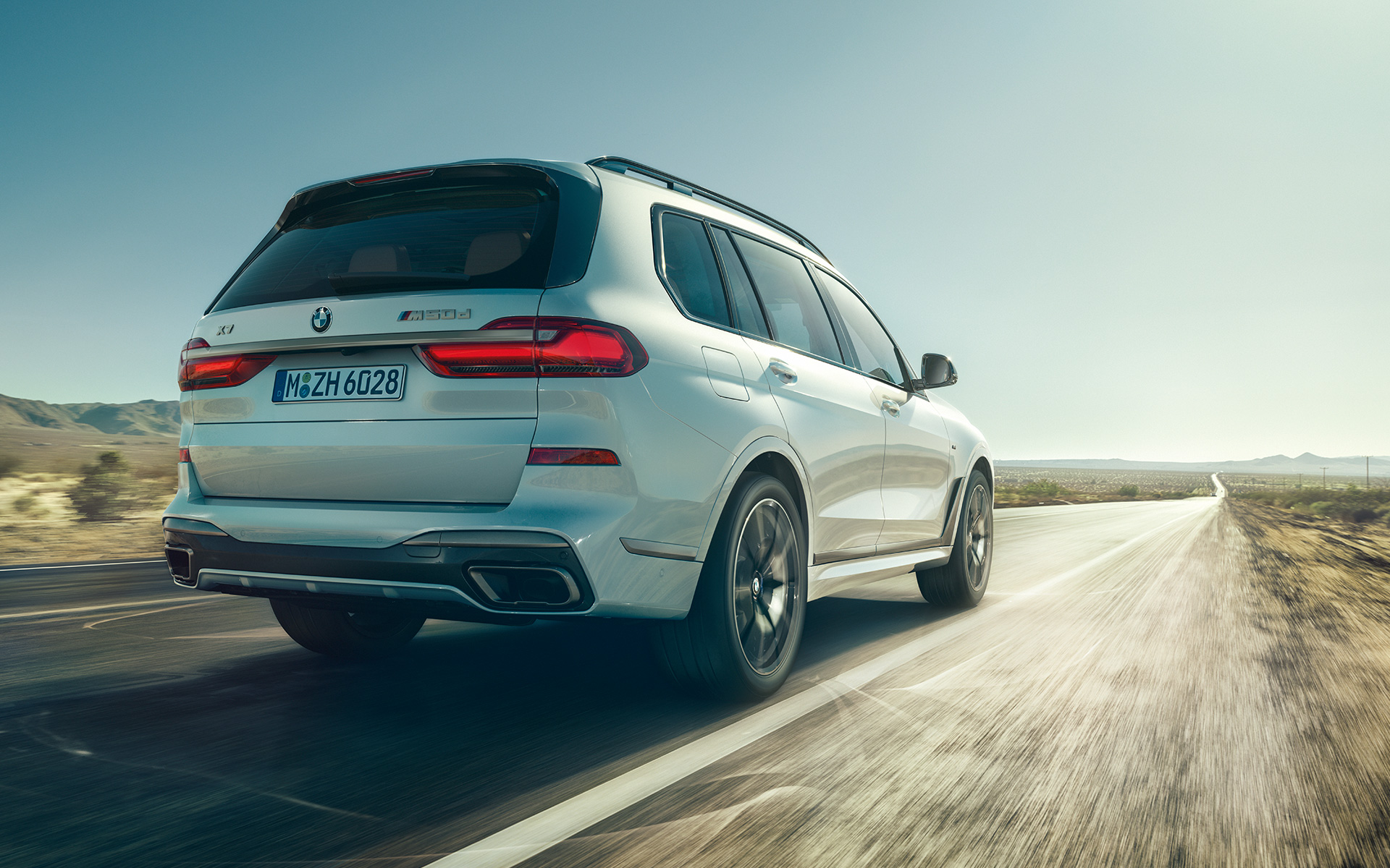 BMW X7 G07, 2019, barva Mineral White, pogled od zadaj med vožnjo BMW X7 G07, 2019, barva Mineral White, pogled od zadaj med vožnjo