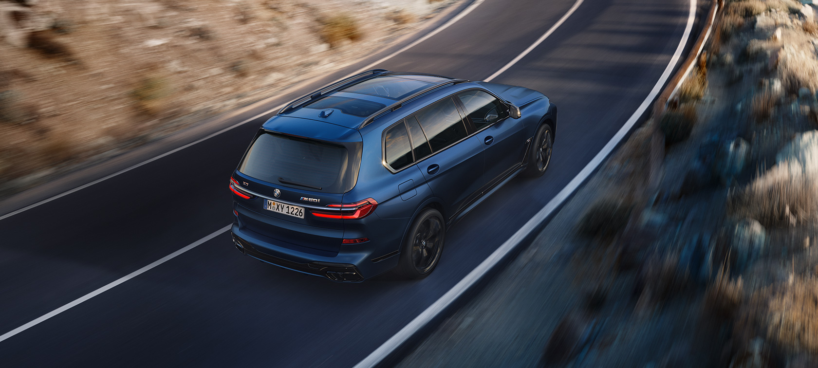 BMW X7 M60i xDrive G07 LCI Frozen Marina Bay Blue tričetrtinski vzvratni pogled vožnja iz ptičje perspektive BMW X7 M60i xDrive G07 LCI Frozen Marina Bay Blue tričetrtinski pogled od zadaj iz ptičje perspektive vožnja po ulici