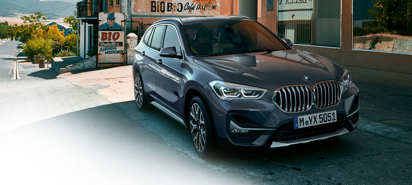 BMW X1, tričetrtinski pogled od spredaj. BMW X1, tričetrtinski pogled od spredaj, stoji pred mestno pokrajino.