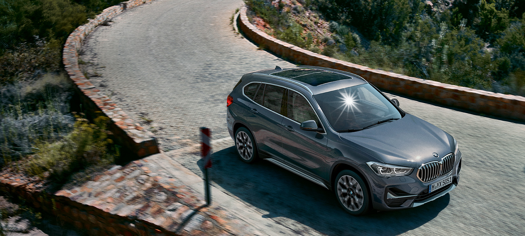 BMW X1, tričetrtinski pogled od spredaj. BMW X1, tričetrtinski pogled od spredaj med vožnjo pred gorsko pokrajino.