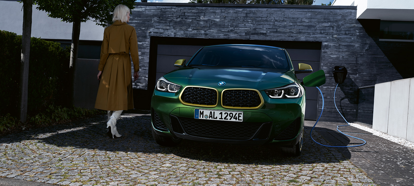 BMW X2, F39, kovinska barva Sanremo Green, pogled od spredaj BMW X2, F39, kovinska barva Sanremo Green, pogled od spredaj med polnjenjem z manekenko na levi strani