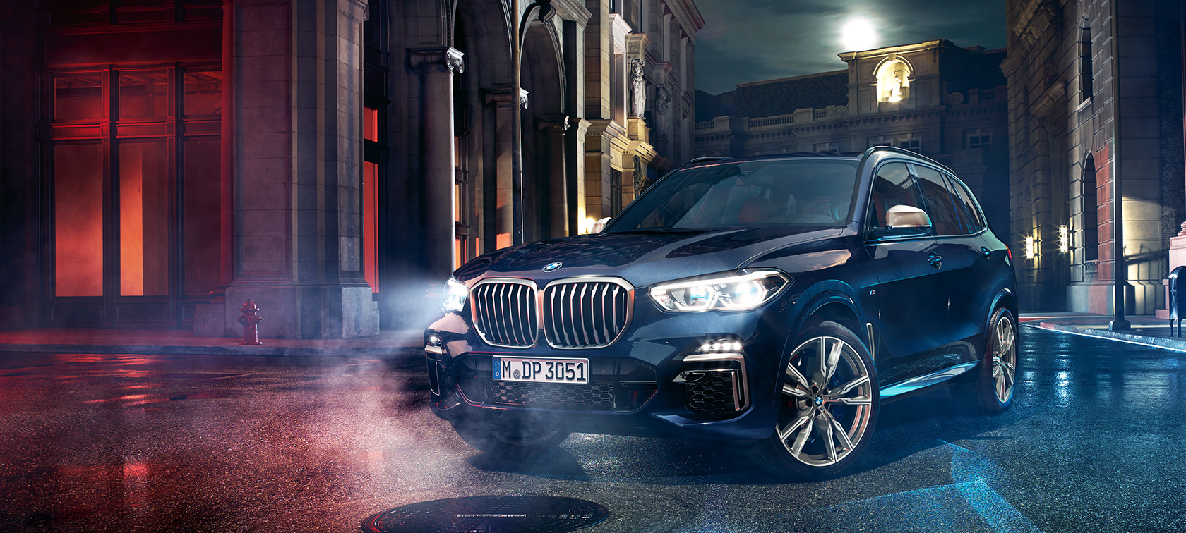 Vozilo BMW X5 M50d na cesti Vozilo BMW X5 M50d stoji na cesti ponoči v mestu