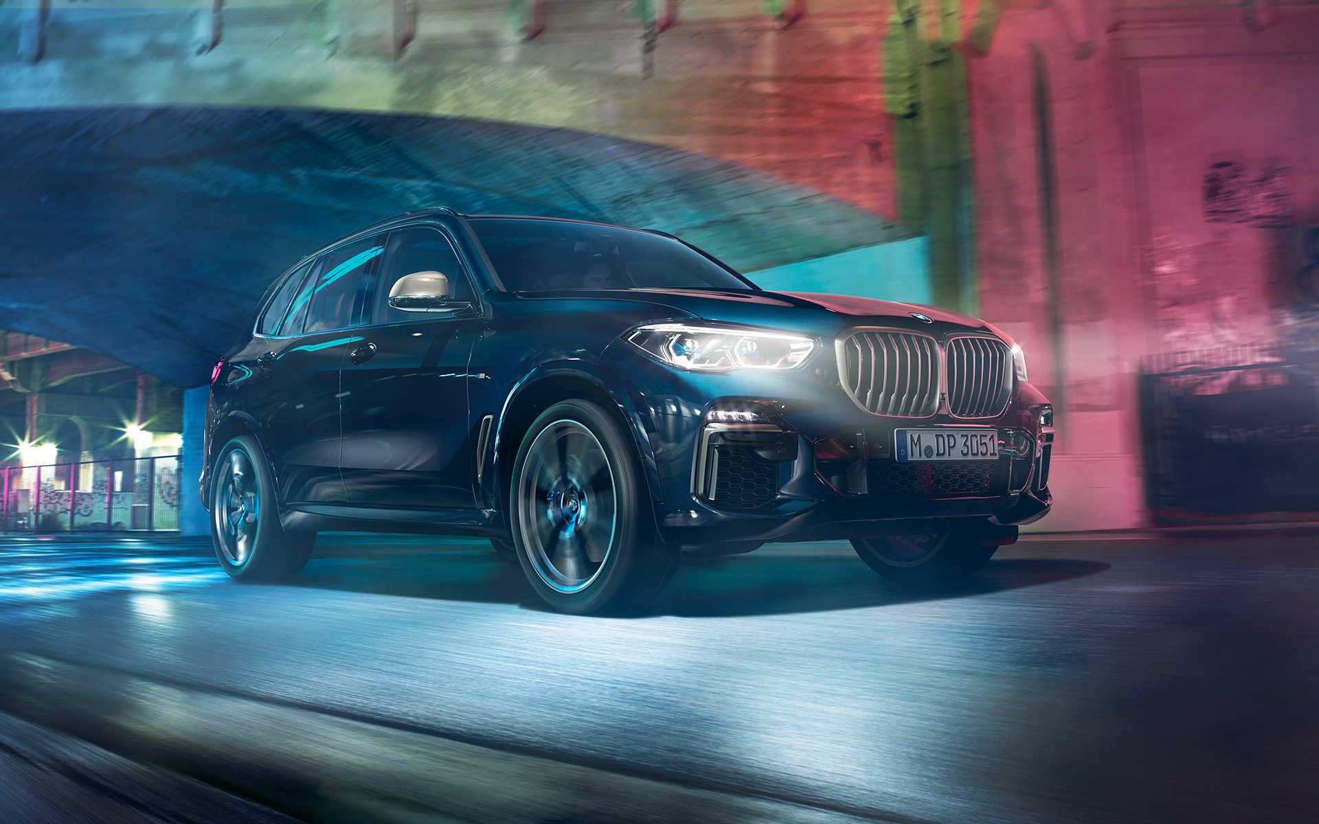 Vozilo BMW X5 M50d v akciji Fotografija vozila BMW X5 med vožnjo ponoči v mestnem okolju