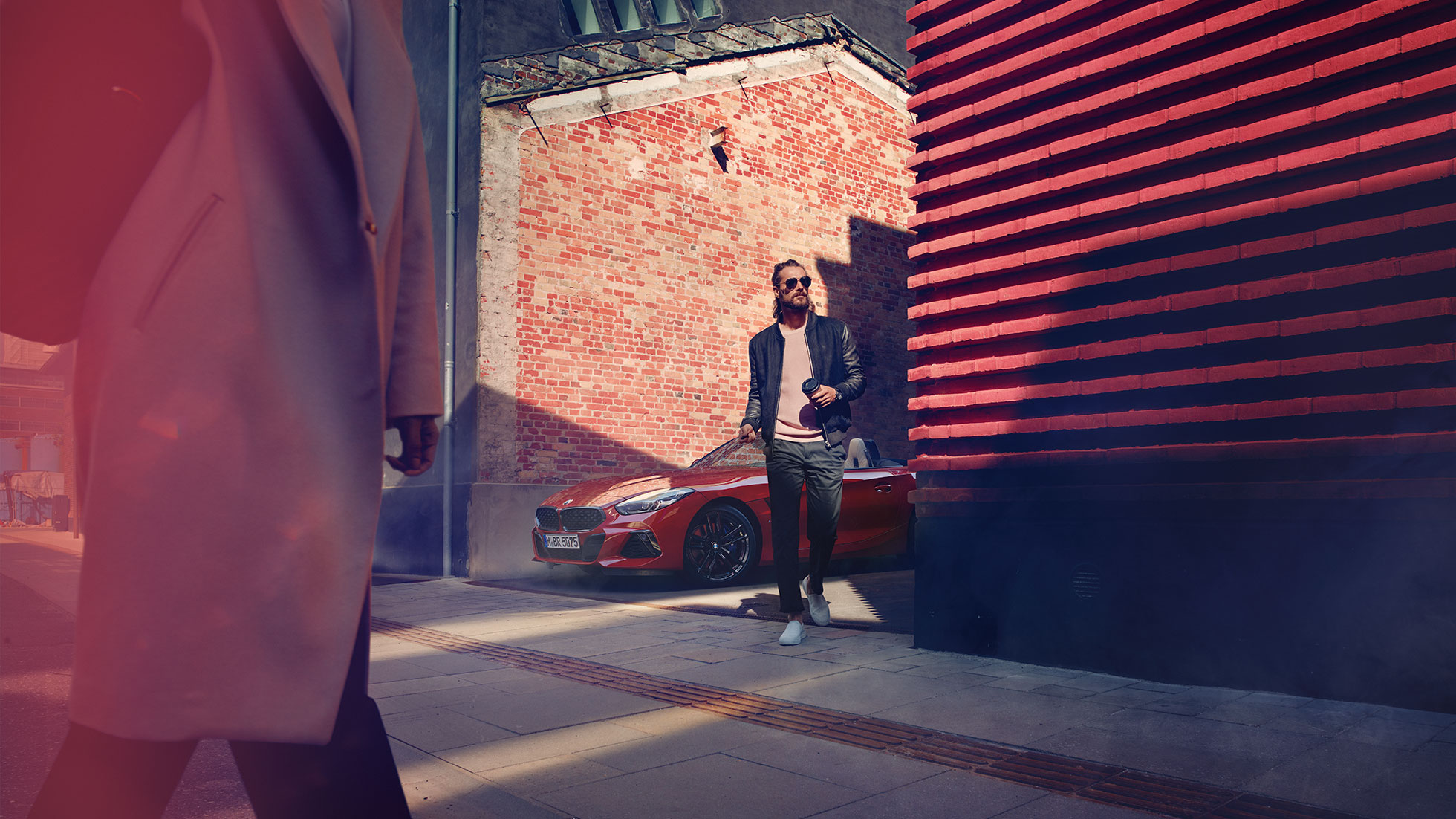 BMW Z4 Roadster v stranski ulici Moški v stranski ulici pred vozilom BMW Z4 Roadster