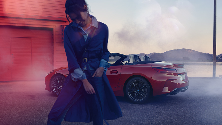 BMW Z4 M40i Roadster (G29) z odprto zložljivo platneno streho BMW Z4 M40i Roadster G29, tričetrtinski pogled od zadaj z odprto zložljivo platneno streho in žensko v ospredju