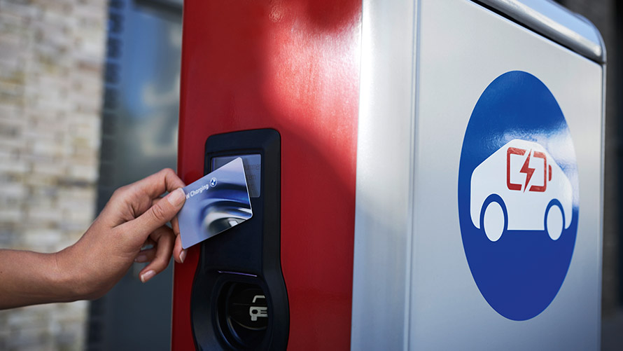 Javno polnjenje s kartico BMW Charging Oseba ima v roki kartico BMW Charging na javni polnilni postaji