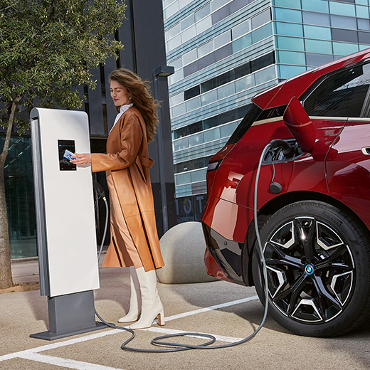 BMW iX, i20 na polnilni postaji, ženska s kartico BMW Charging