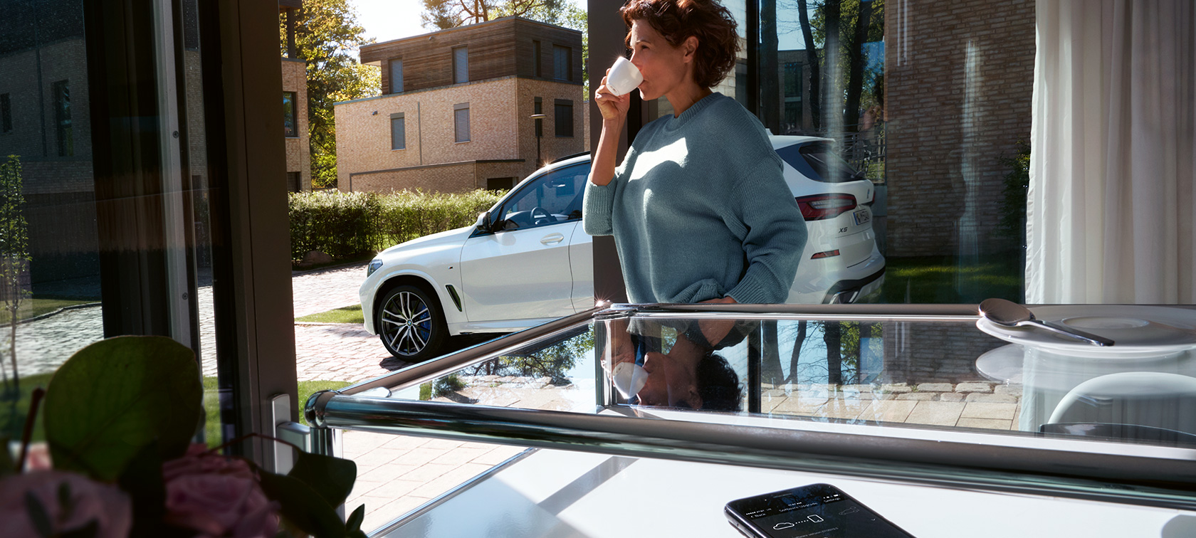 BMW Remote Software Upgrade Ženska pije iz lončka in čaka, da BMW Remote Software Upgrade posodobi programsko opremo njenega BMW X5