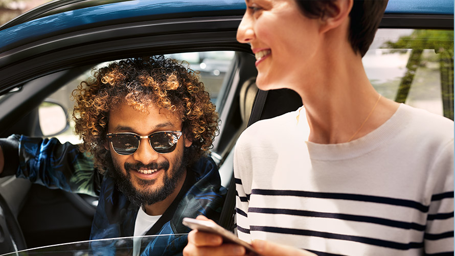 BMW Connected Moški v BMW in ženska zunaj vozila uporabljata BMW Connected na pametnem telefonu