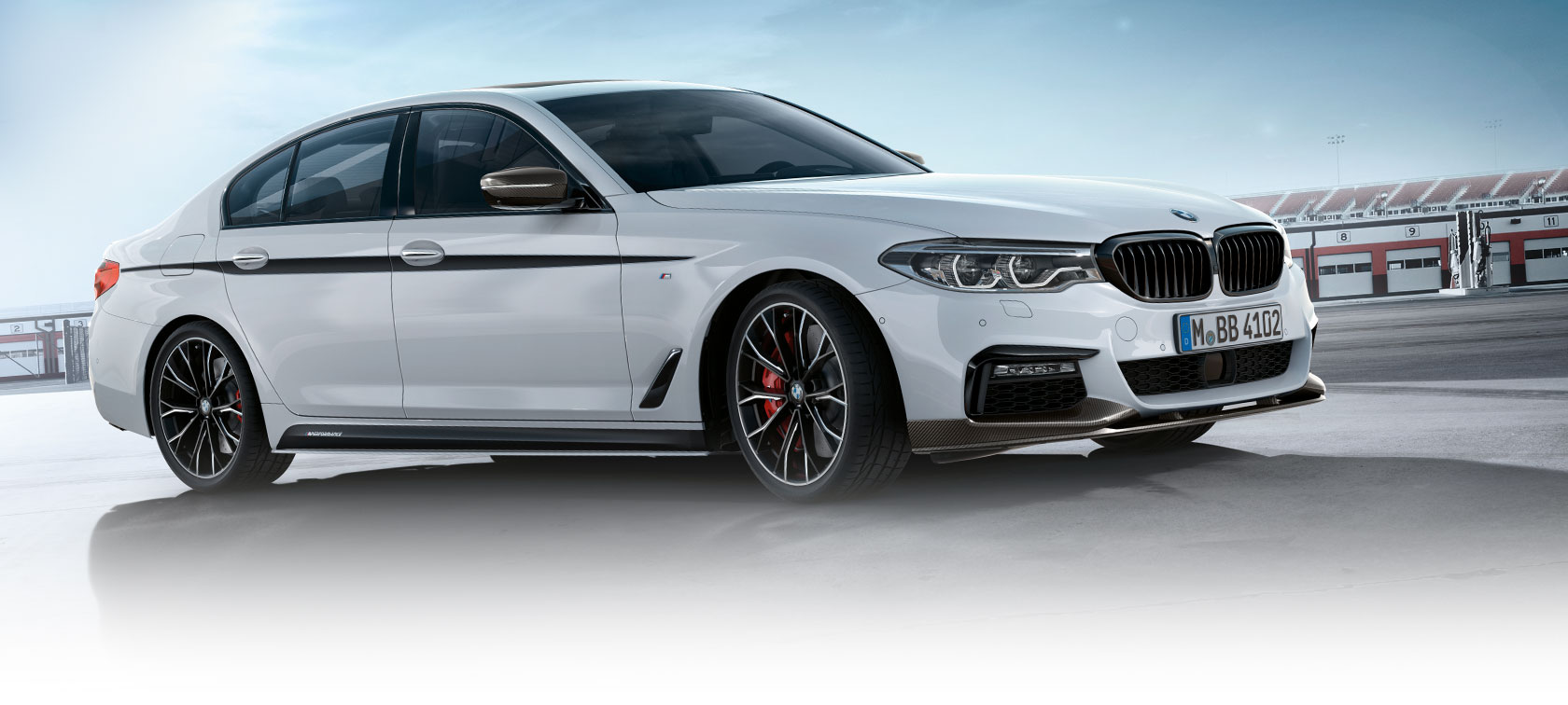 BMW serije 3 limuzina, program M Performance Parts. Pogled od strani na model BMW serije 3 limuzina na parkirišču pod modrim nebom.