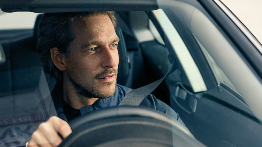 Moški vozi BMW Moški vozi BMW in gleda skozi vetrobransko steklo