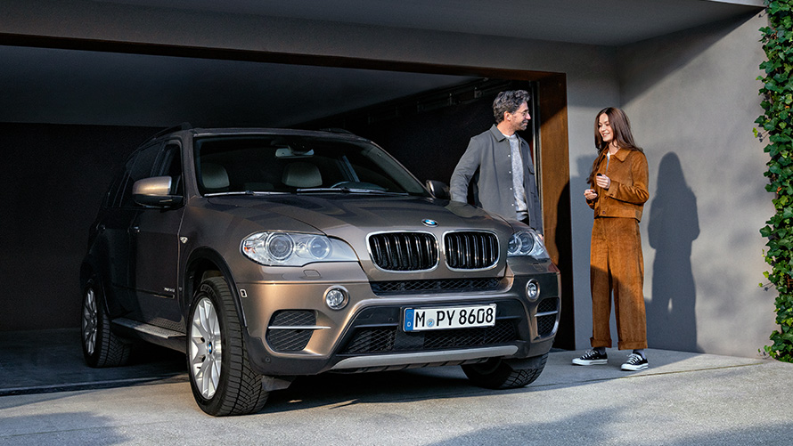 BMW je parkiran pred garažo z manekenkami BMW Value Service, BMW je parkiran pred garažo z manekenkami
