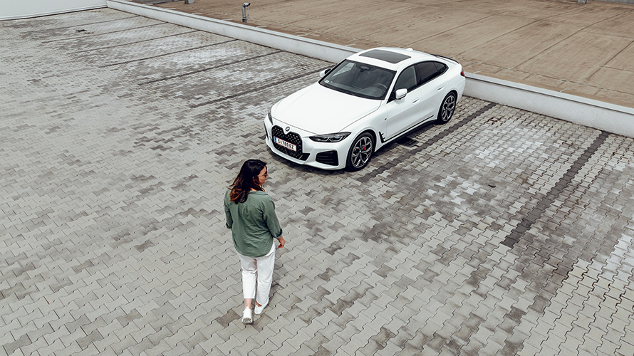 Ženska hodi proti BMW i4 in glede na levo stran. Ženska hodi proti BMW i4 in glede na levo stran.