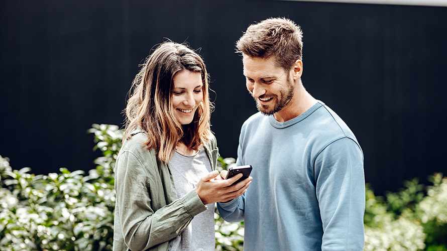 Moški in ženska gledata v ženski pametni telefon. On kaže na zaslon. Moški in ženska gledata v ženski pametni telefon. On kaže na zaslon.