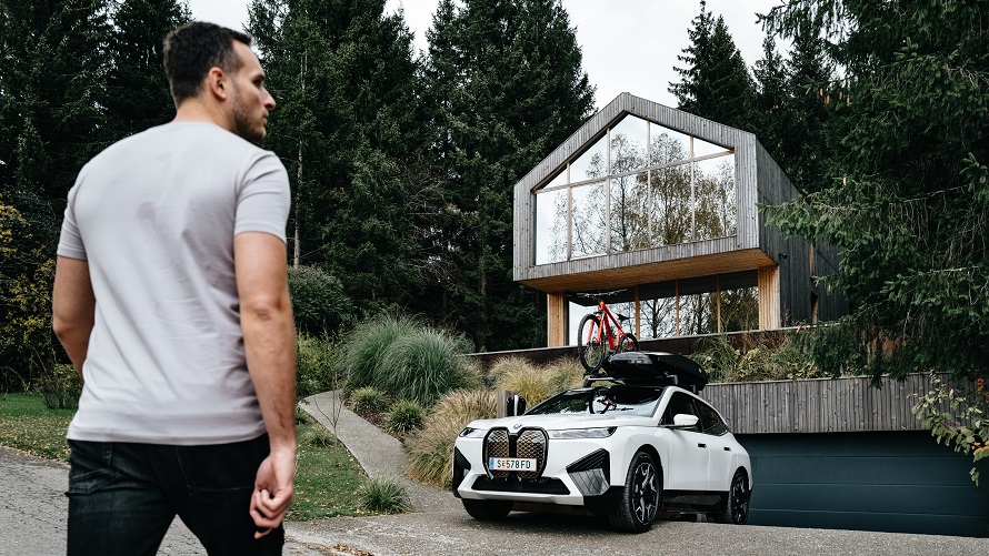 Moški hodi proti BMW iX, ki je parkiran pred hišo. Moški hodi proti BMW iX, ki je parkiran pred hišo.