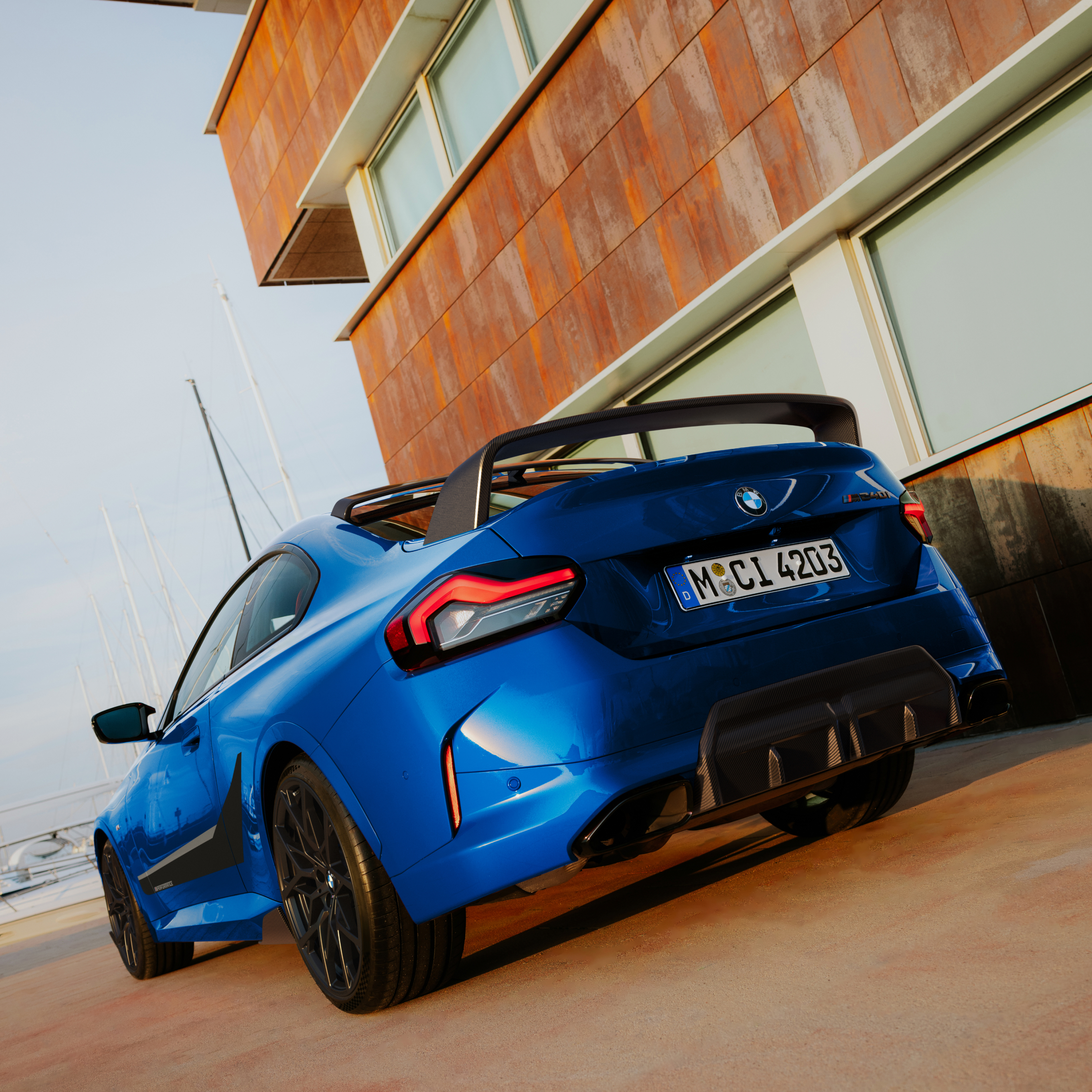 BMW z zadnjim spojlerjem M Performance, parkiran pred hišo